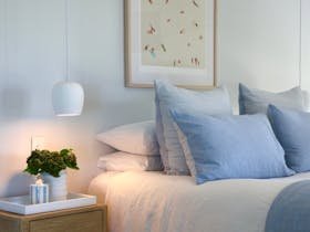 Queen bedroom with soft linen bedding, bedside lamps and coastal artwork at Harolds on the Hill