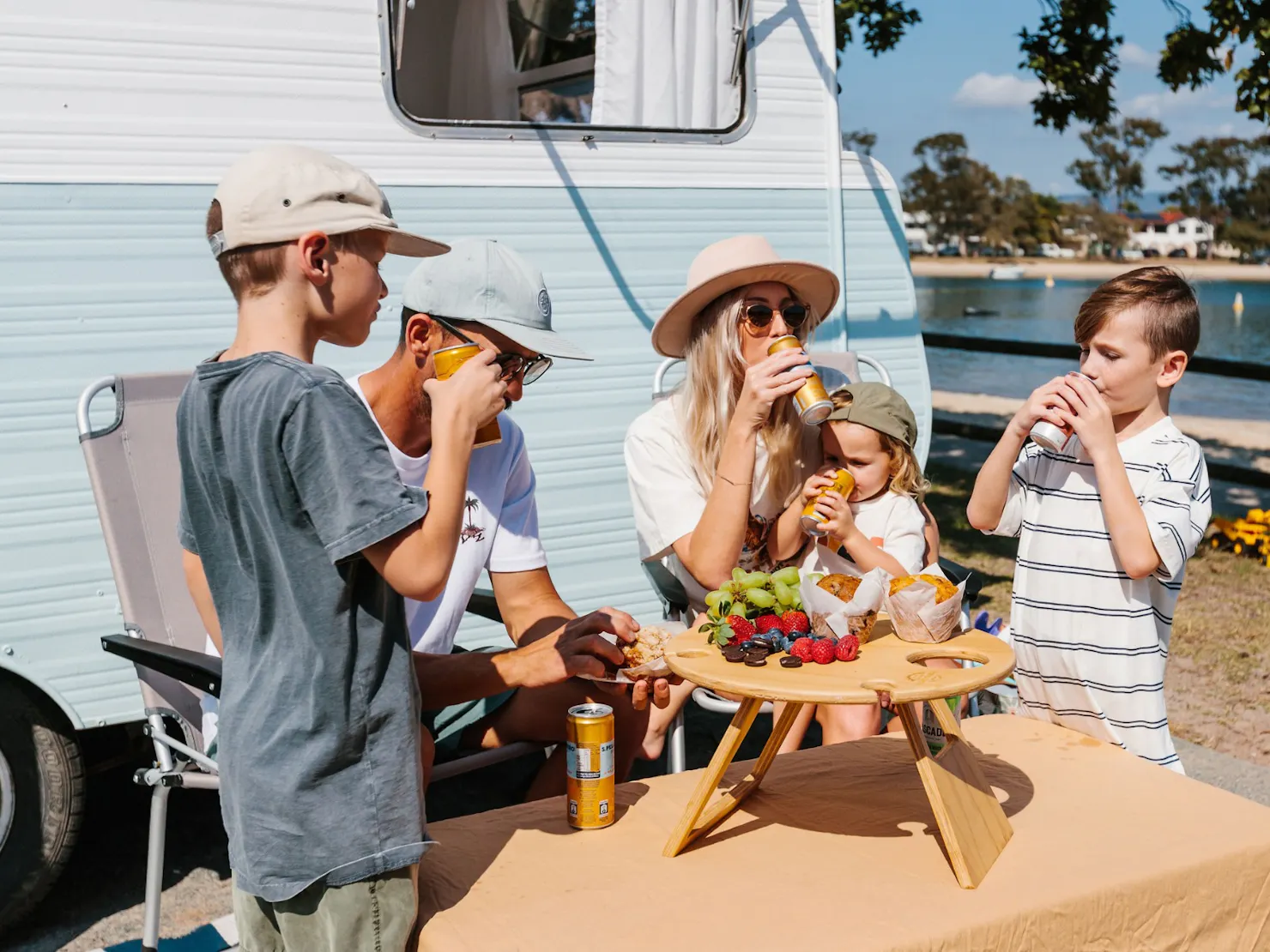 A family sits in front of their caravan eating and drinking