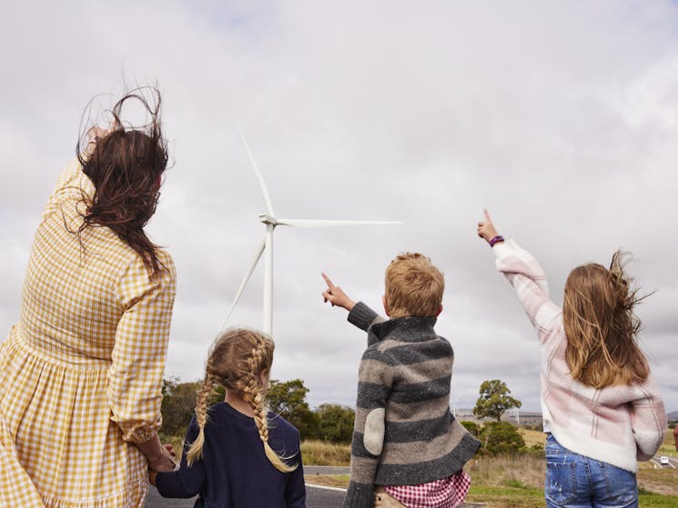 family pointing a large wind turbine