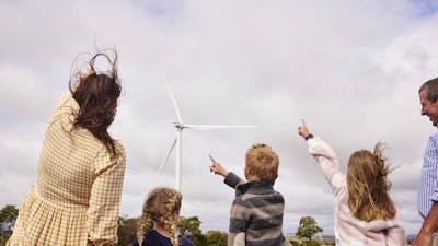 family pointing a large wind turbine