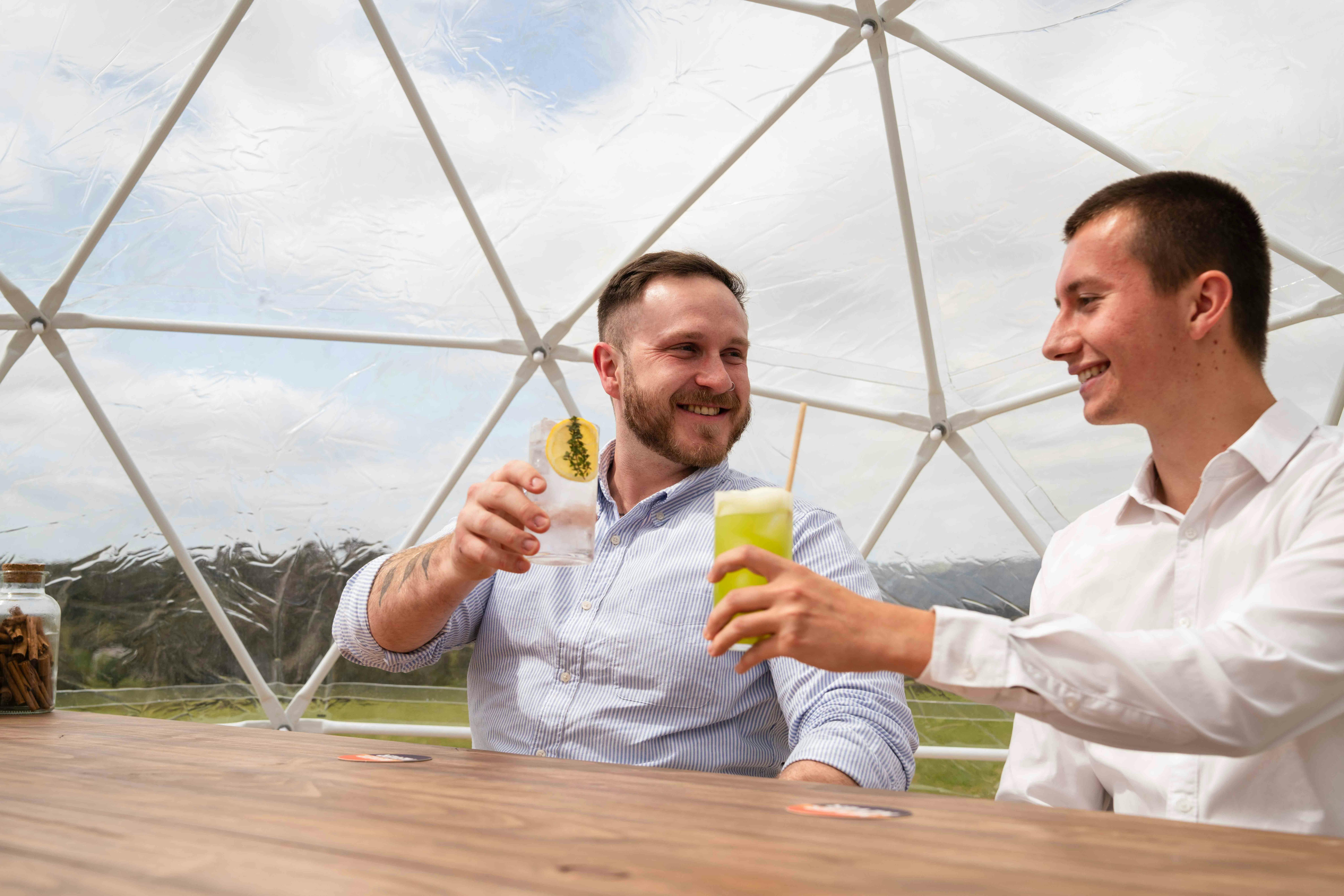 two men cheersing gin glasses with smiles