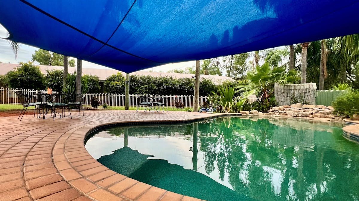 A lagoon style under-cover pool with waterfall at one end.  Paved seating area with lawns and garden