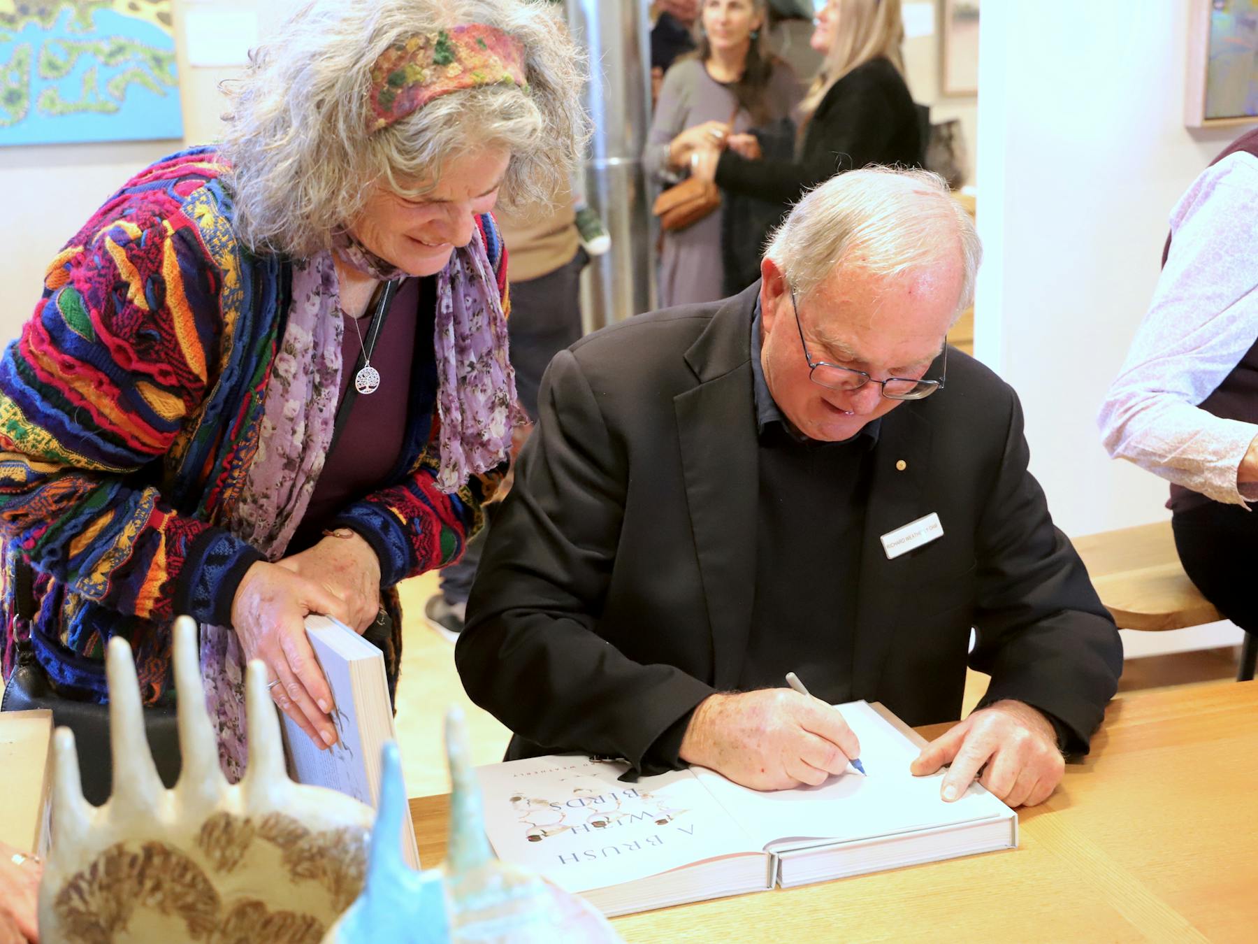 Image of artist and author Richard Weatherly OAM signing a book