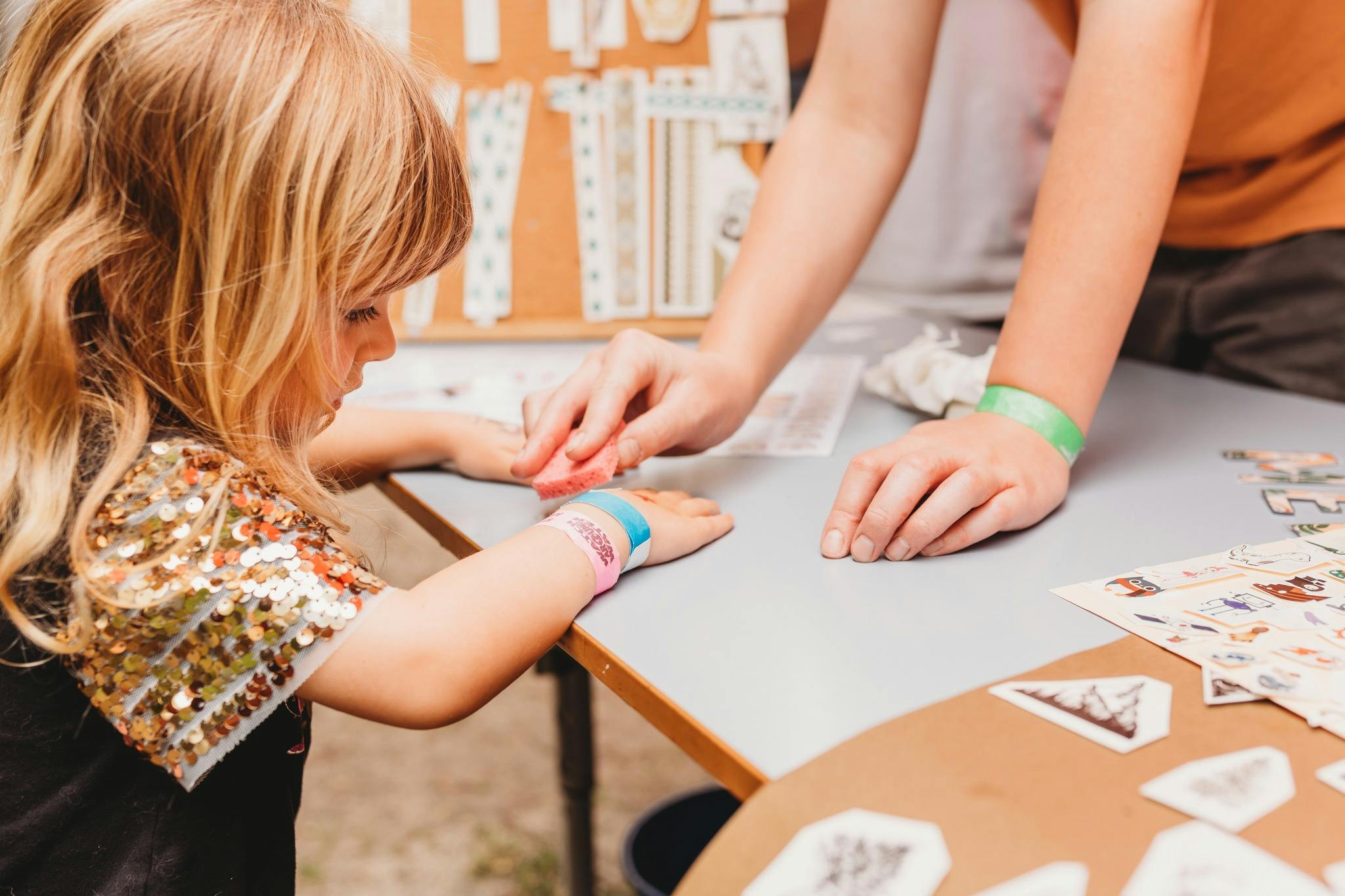 Girl sitting at table,  having a sponge applied to the back of her wrist