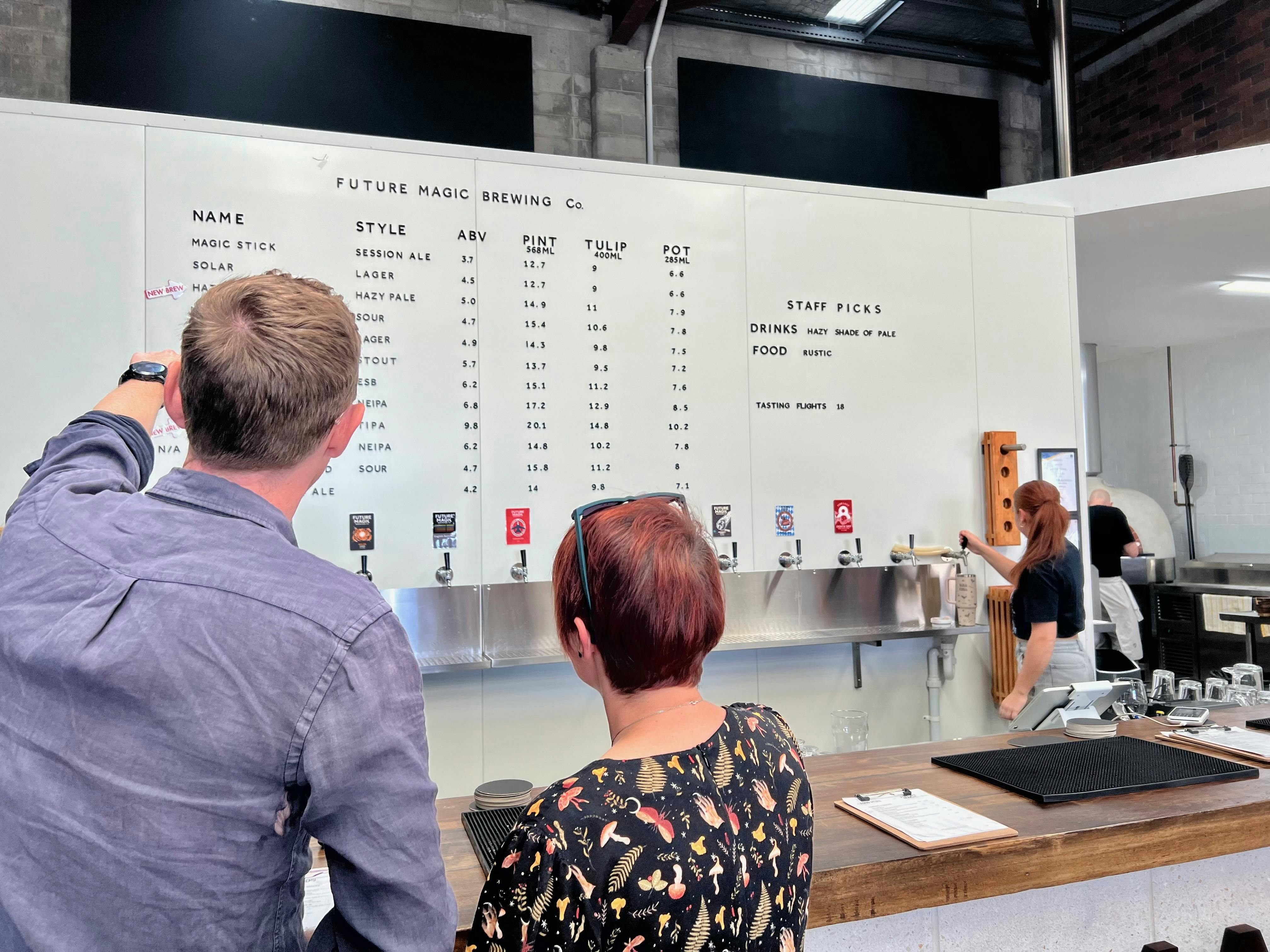 Two people at the bar at Future Magic Brewing Co ordering a tasting paddle