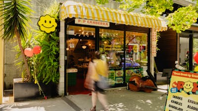 A sunny day outside POP Canberra, showcasing its bright yellow awning, cheerful signage. Welcome.
