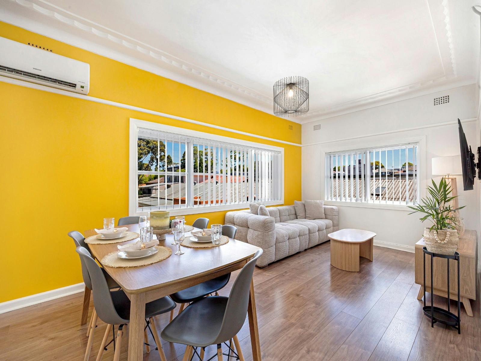 Dining area adjacent to living space with table setting and split system air-conditioning.