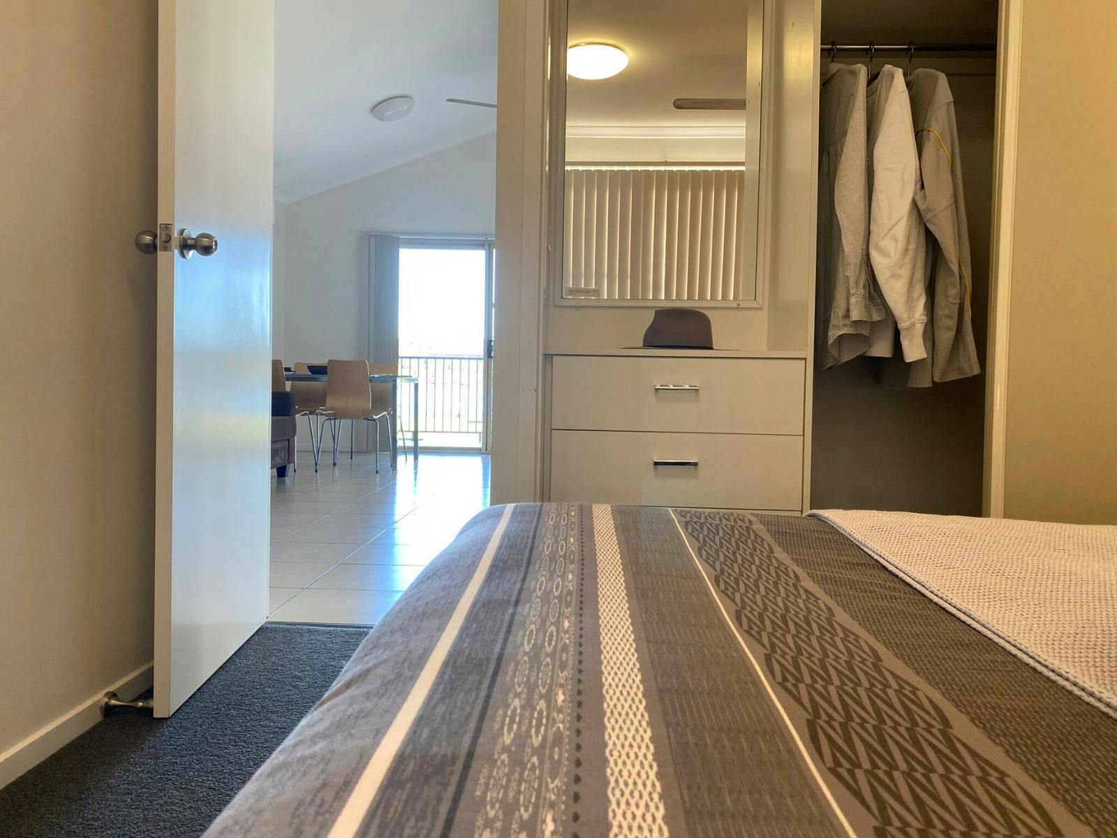 Master bedroom with view of open closet and doorway leading to living area with natural light.