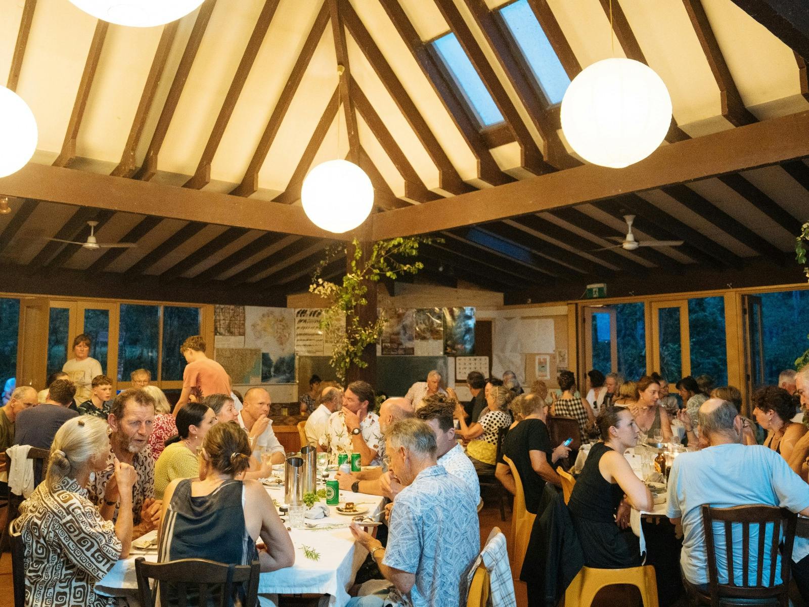 People seated at long tables for dinner in Wangat Lodge dining and common room