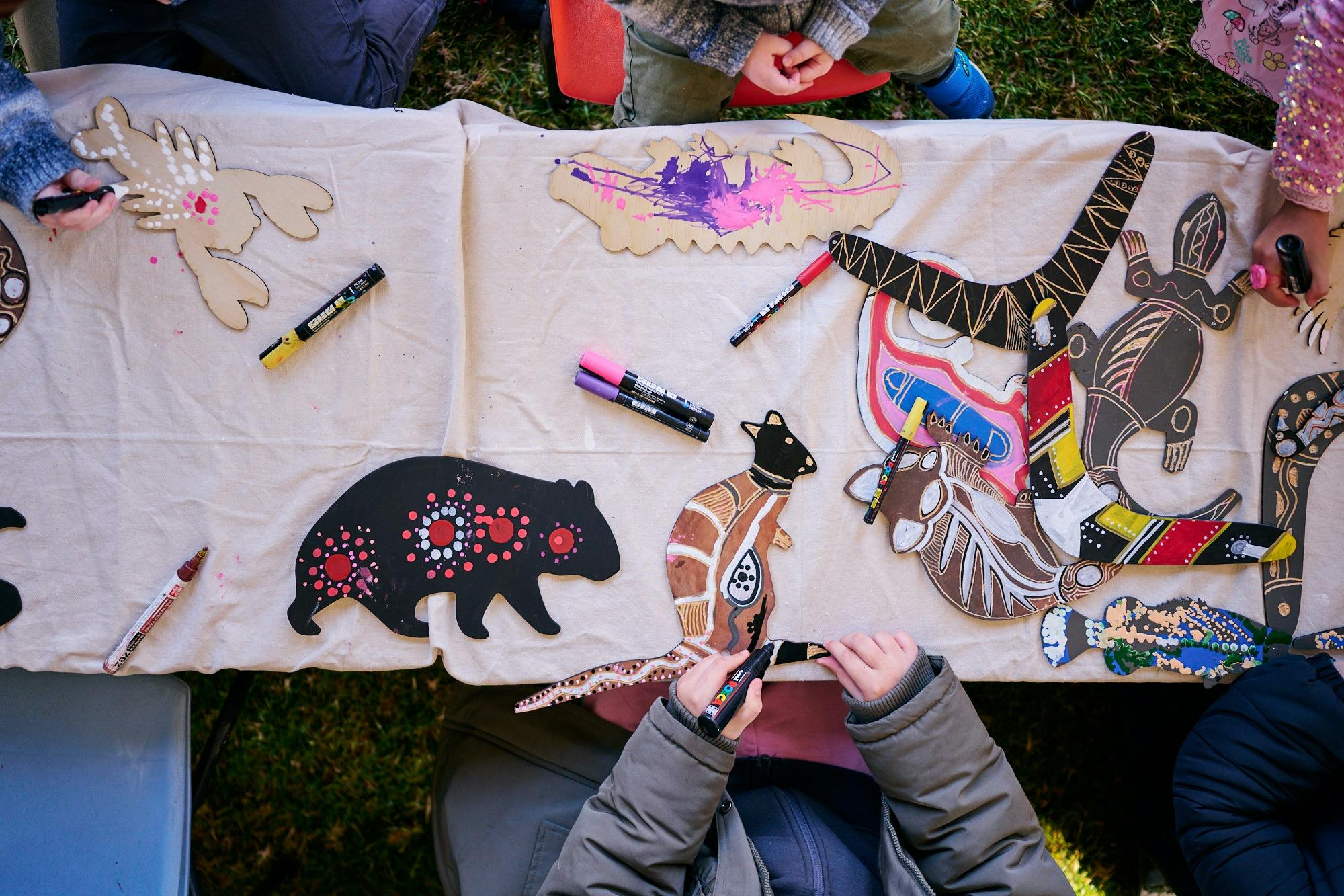 Children decorating wooden animal cutouts with colorful markers during an art activity at a table