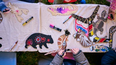 Children decorating wooden animal cutouts with colorful markers during an art activity at a table