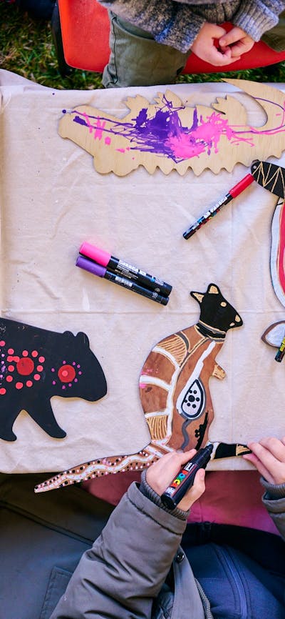 Children decorating wooden animal cutouts with colorful markers during an art activity at a table