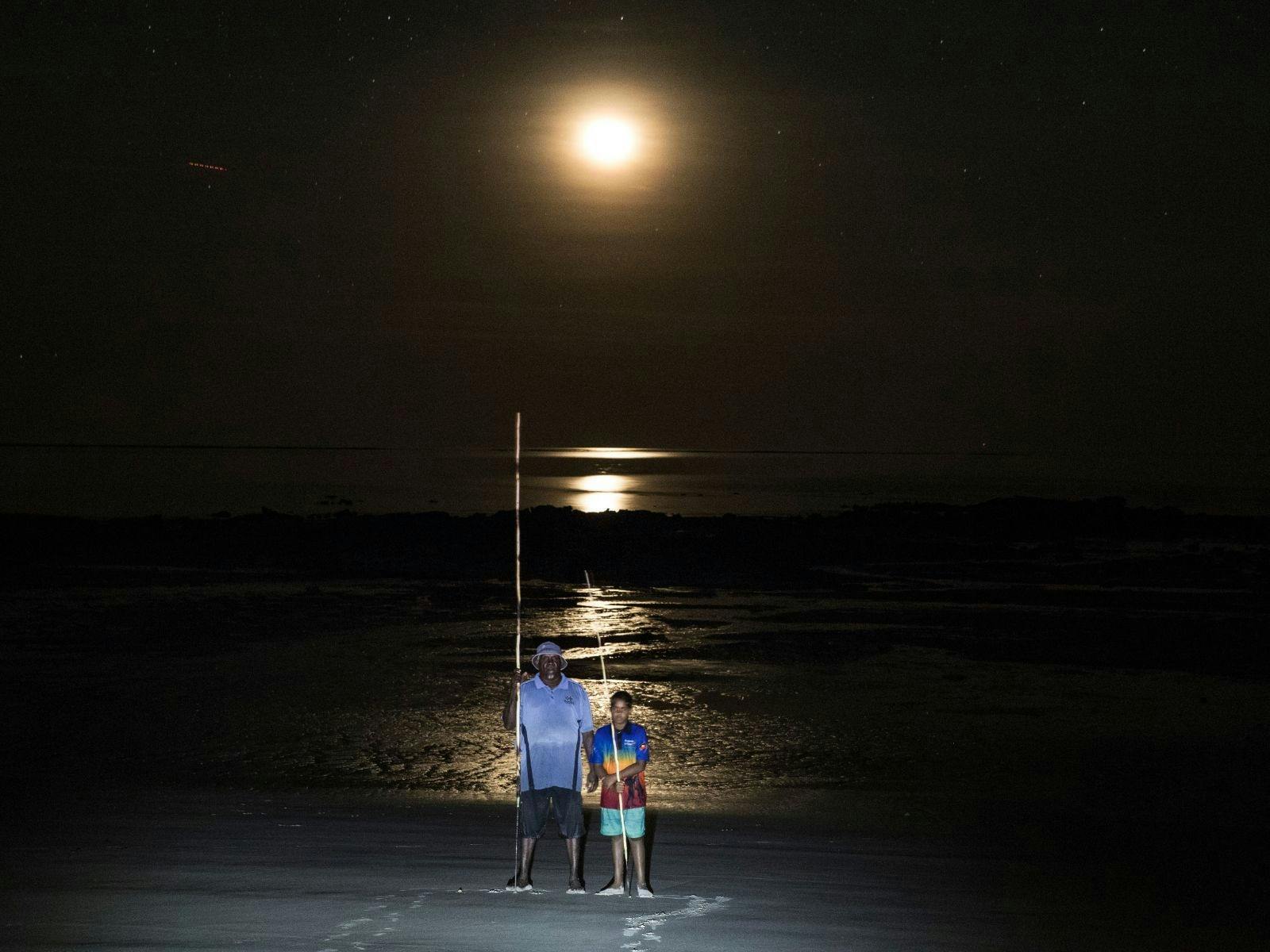 Bundy and boy standing on beach below full moon.