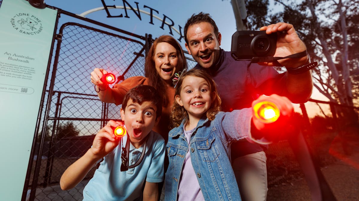 Young family with red-light torches at the entry gates to Nocturnal