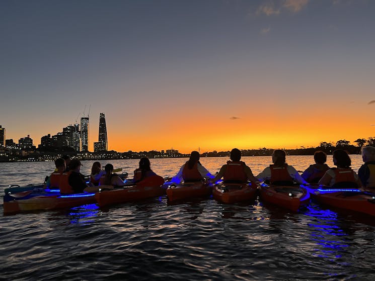 kayakers line up to enjoy the sun set over Sydney Habrour