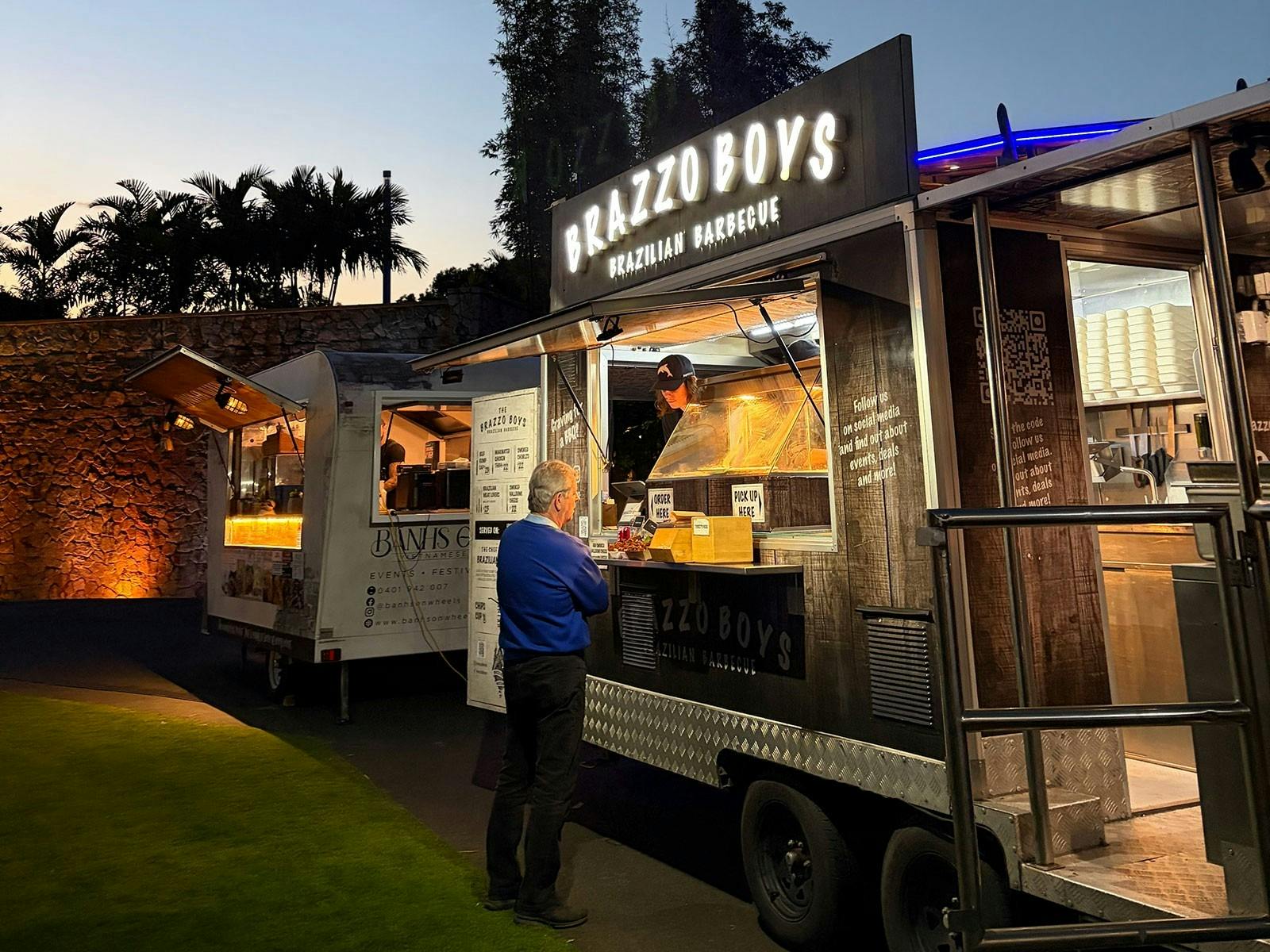 Brazzo Boys food truck at night next to lawn area with lit signage