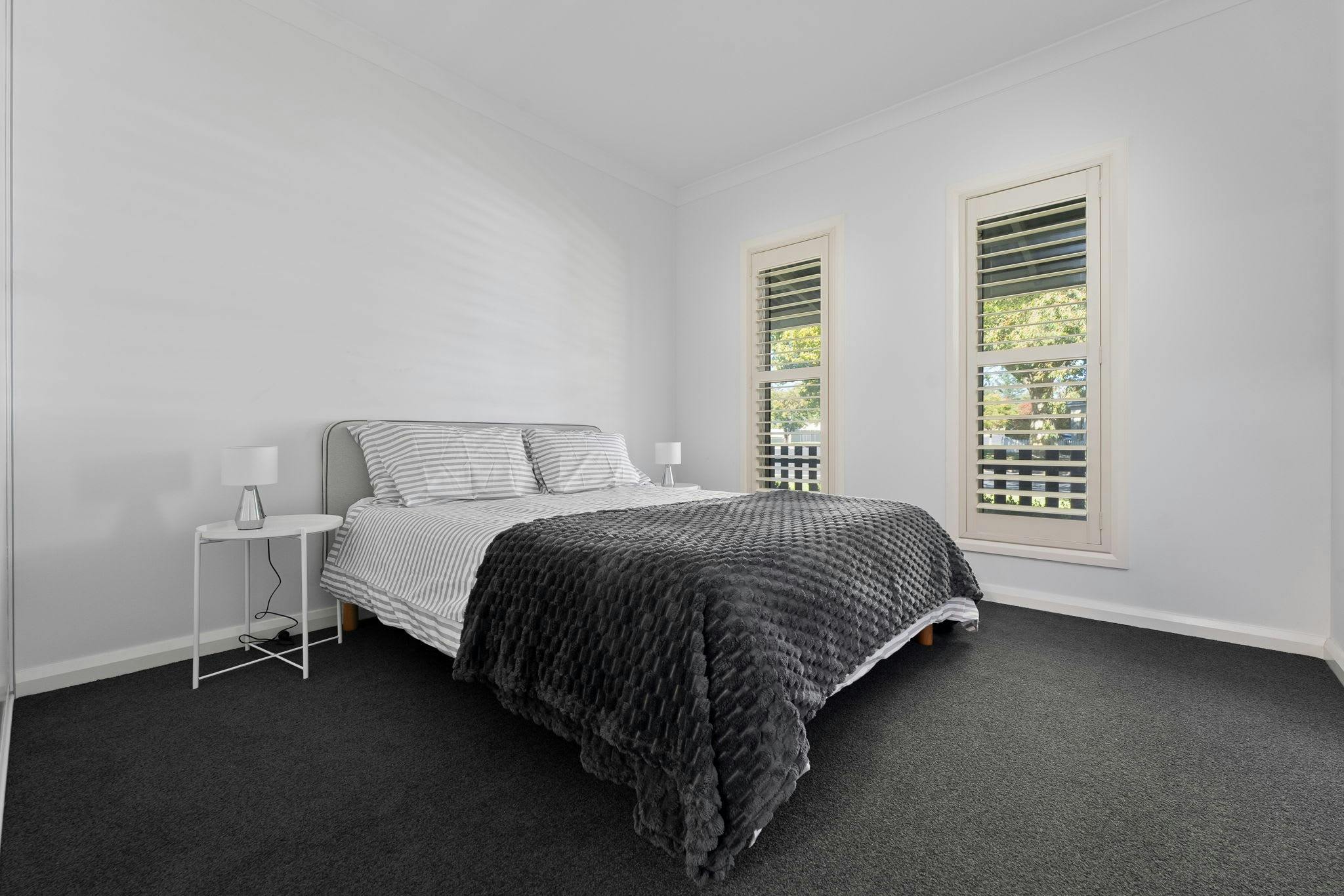 King bed with stripe sheets, and 2 windows facing the front of the house, ensuite and WIR