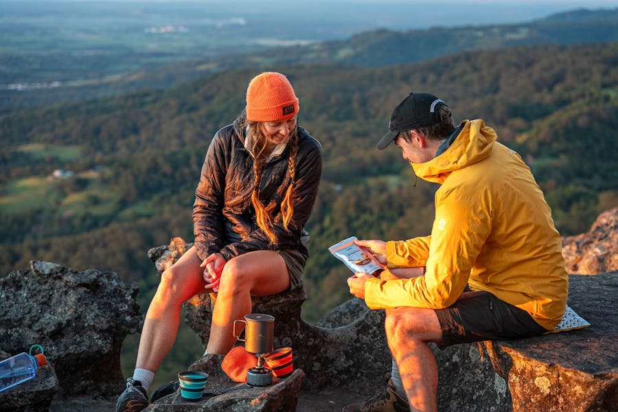 A man and woman prepare to have breakfast after hiking up to a lookout