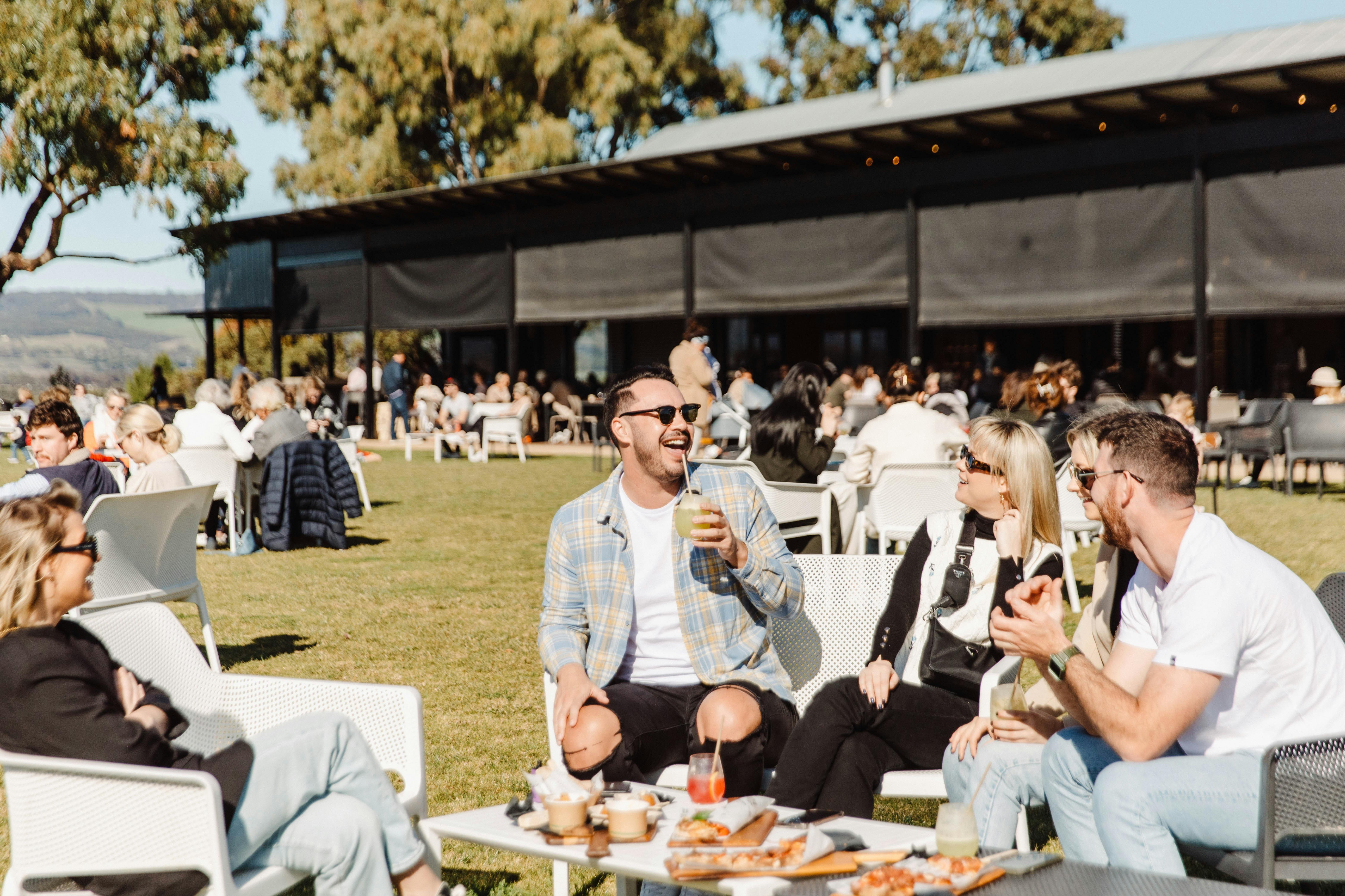 Visitors enjoying cocktails and shared food on the lawn at Never Never Distilling in McLaren Vale