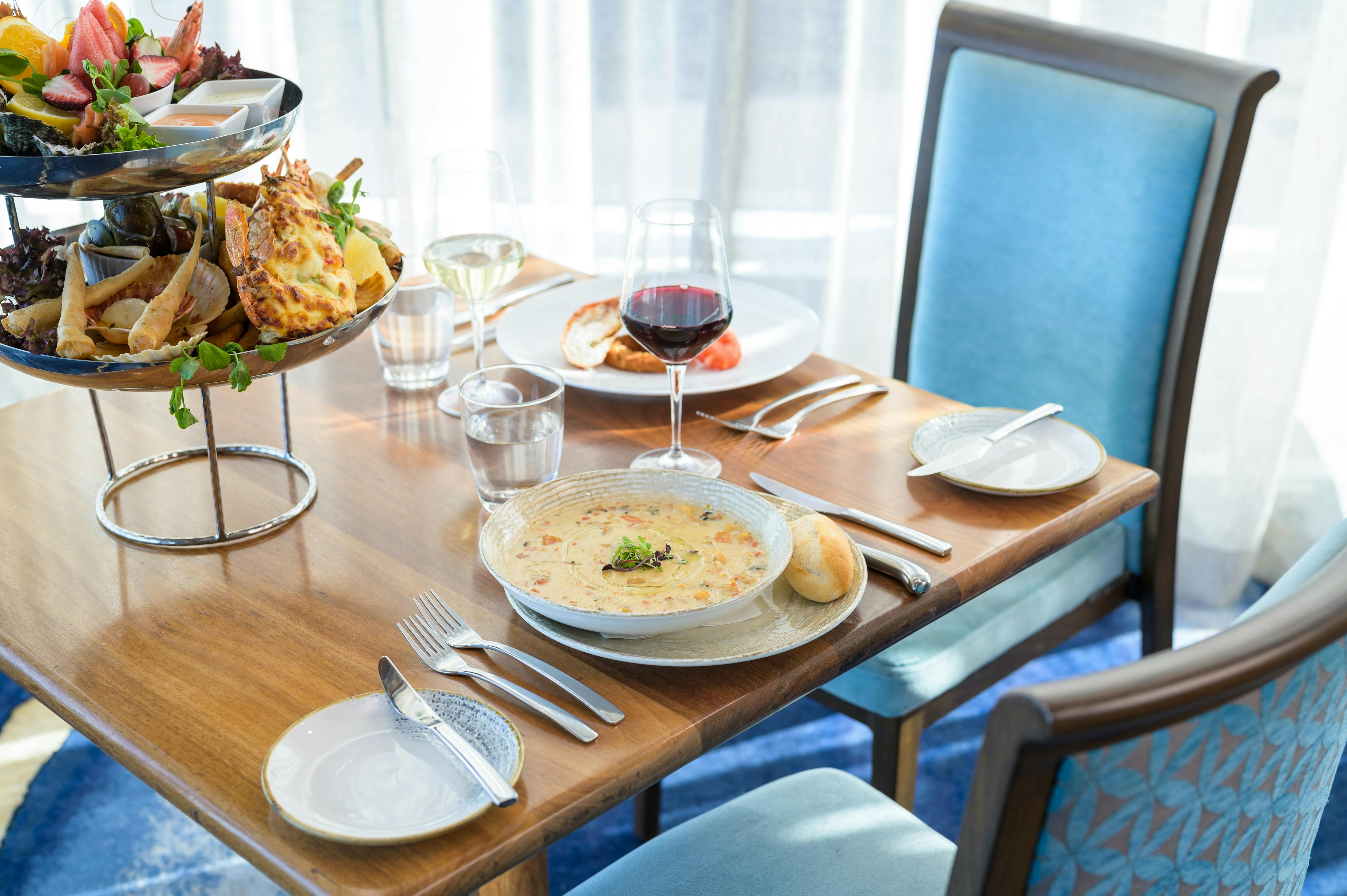 Table setting with Seafood tower and seafood chowder with glasses of wine