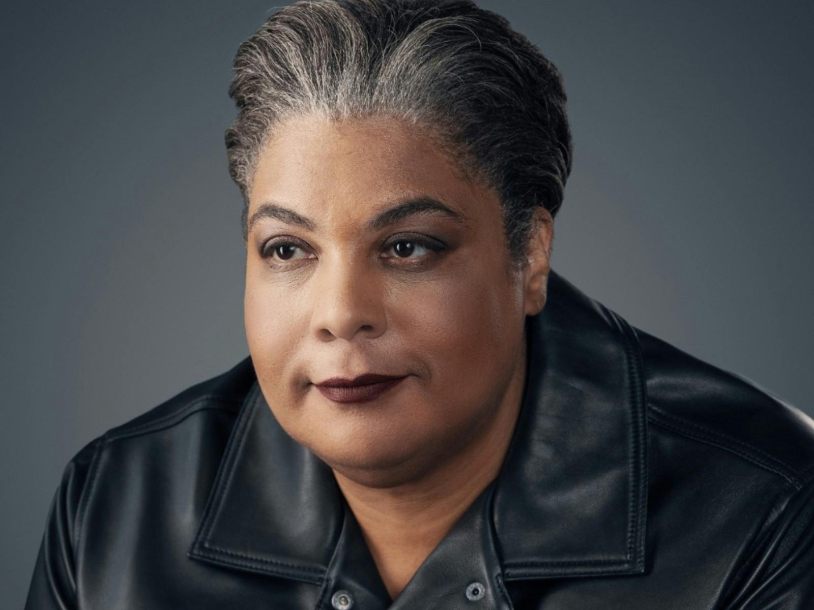 Close-up portrait of a woman with short gray hair wearing a black leather jacket, looking at camera.