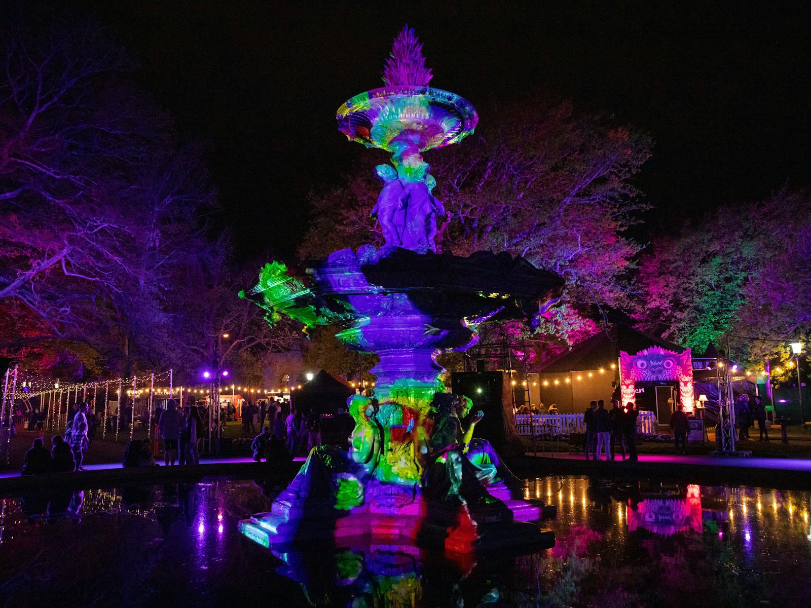 Darkly lit fountain with colourful projection art