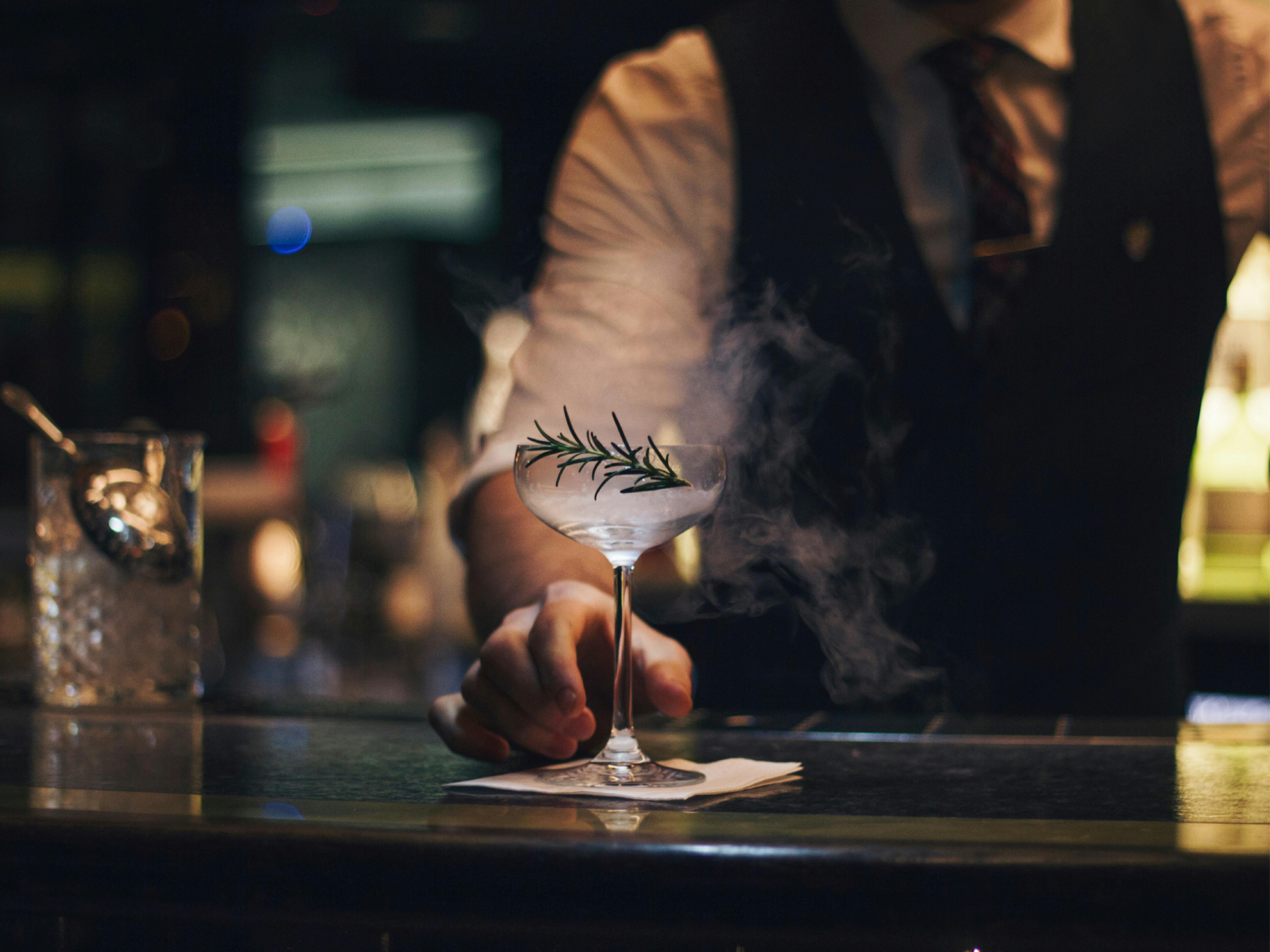 Cocktail bar and bartender handing cocktail over