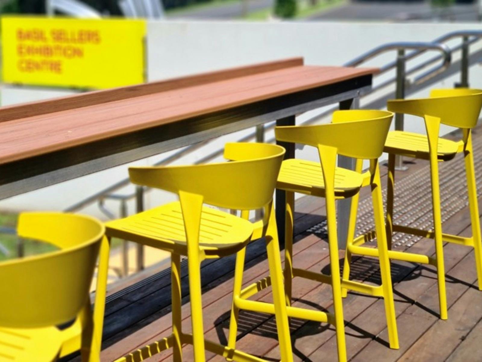Four yellow chairs lined up to a long bench.