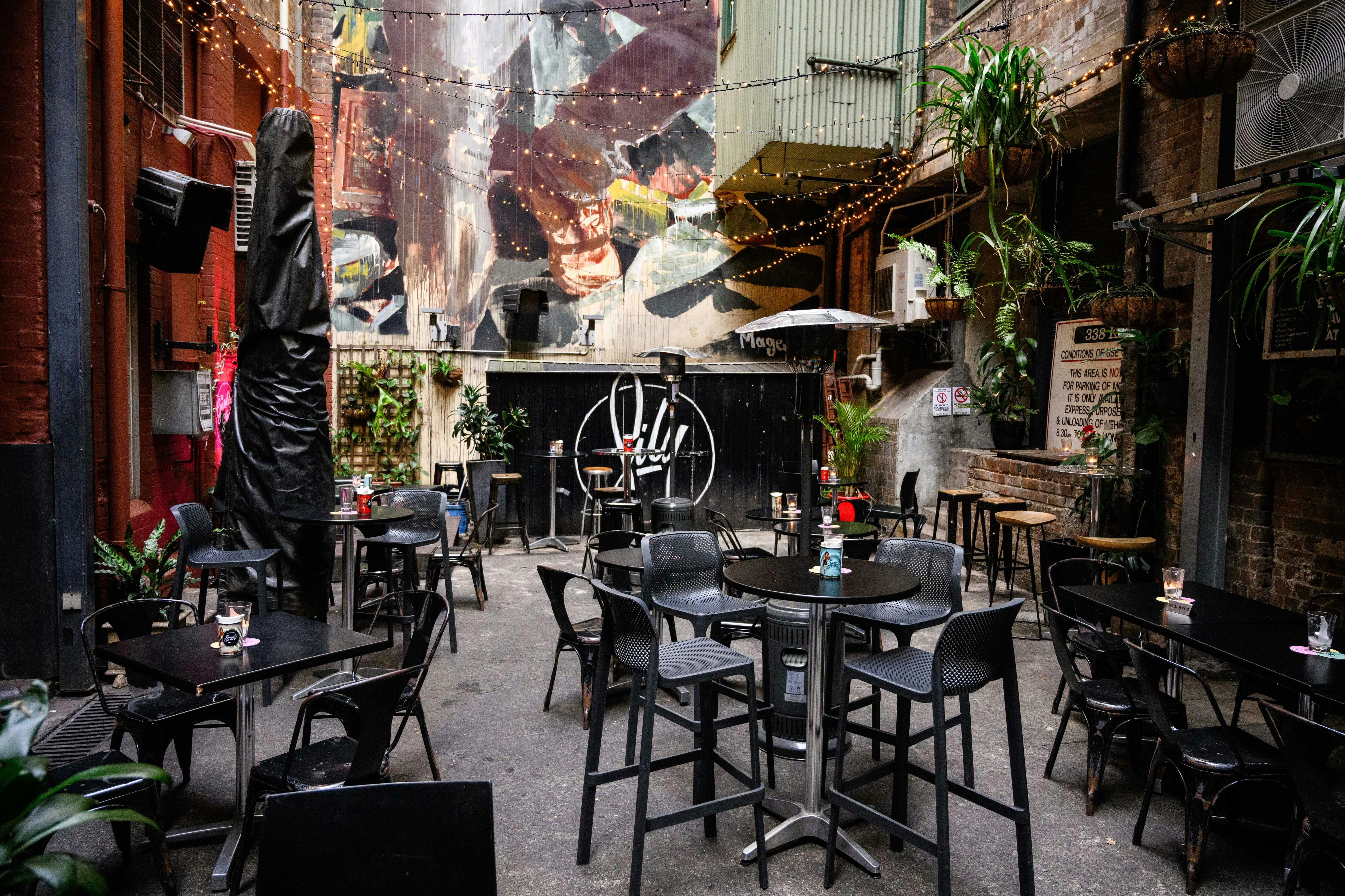 庭院座位區，擺放著高低桌、懸掛植物和壁畫