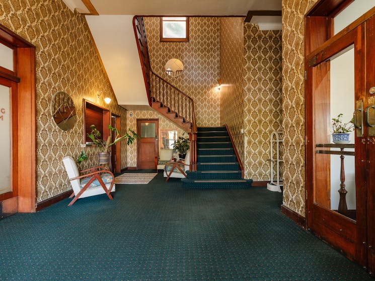Entrance hall green carpet tall staircase gold wallpaper