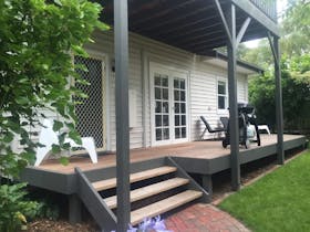 Image of weatherboard home with verandah and outdoor furniture surrouded by garden