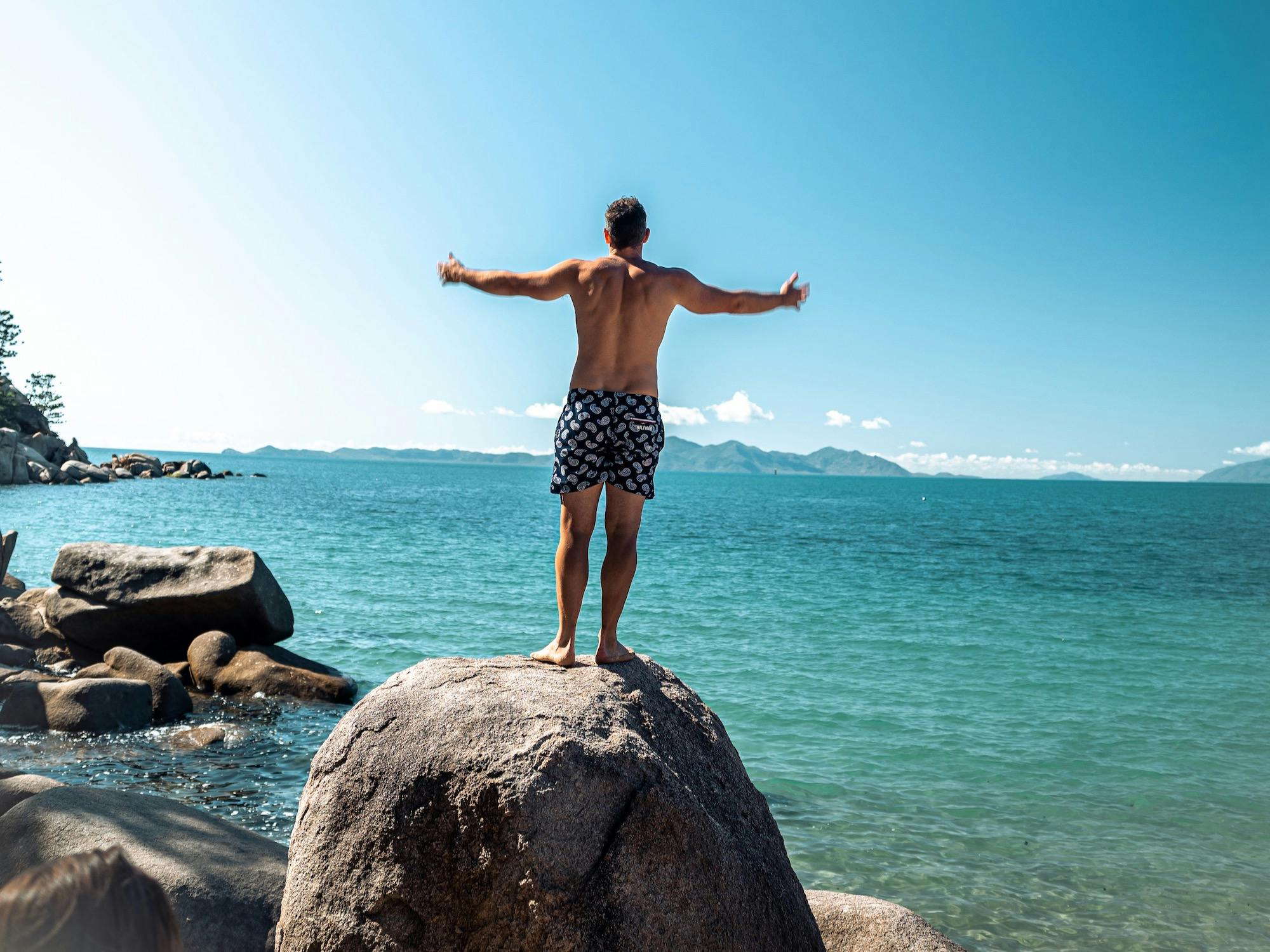 Man on boulder looking out to sea