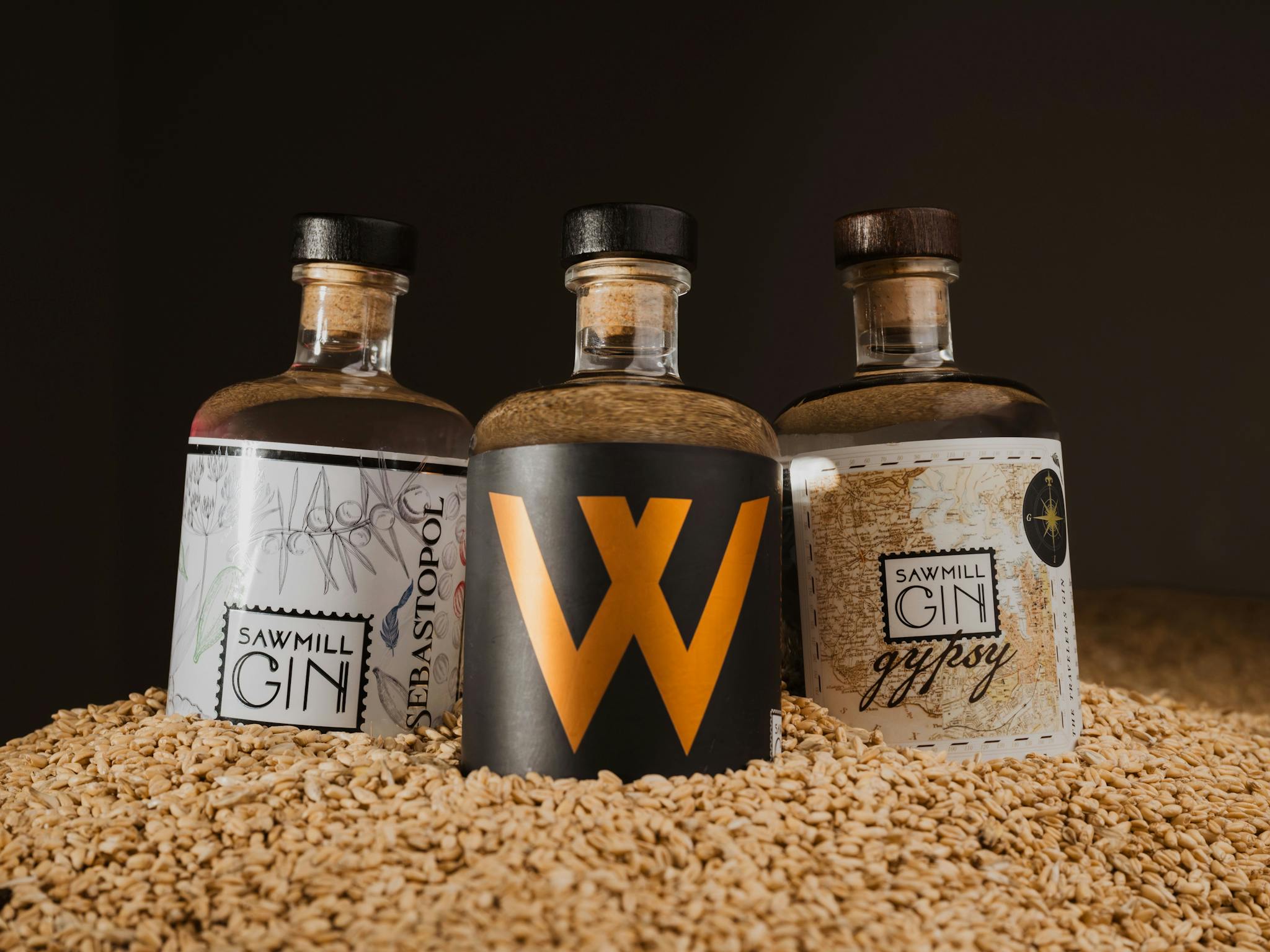 Trio of Sawmill Gin bottles nested on wheat