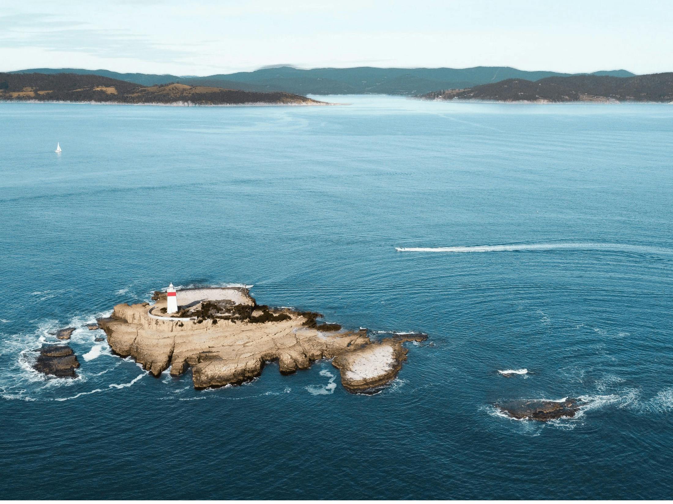 Aerial view of Iron Pot Lighthouse on a rocky outcrop in open water.