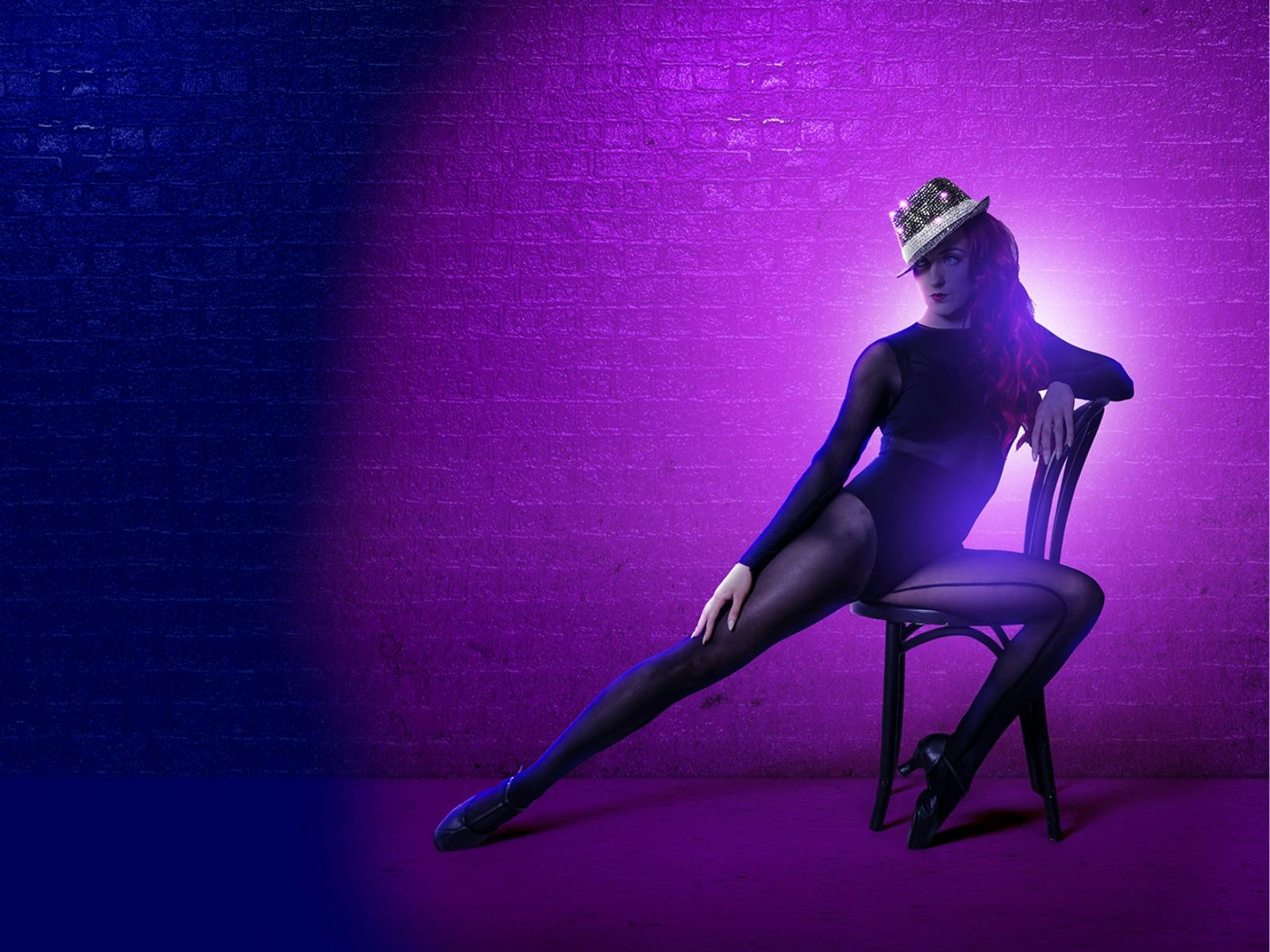 Person leaning on chair with purple background
