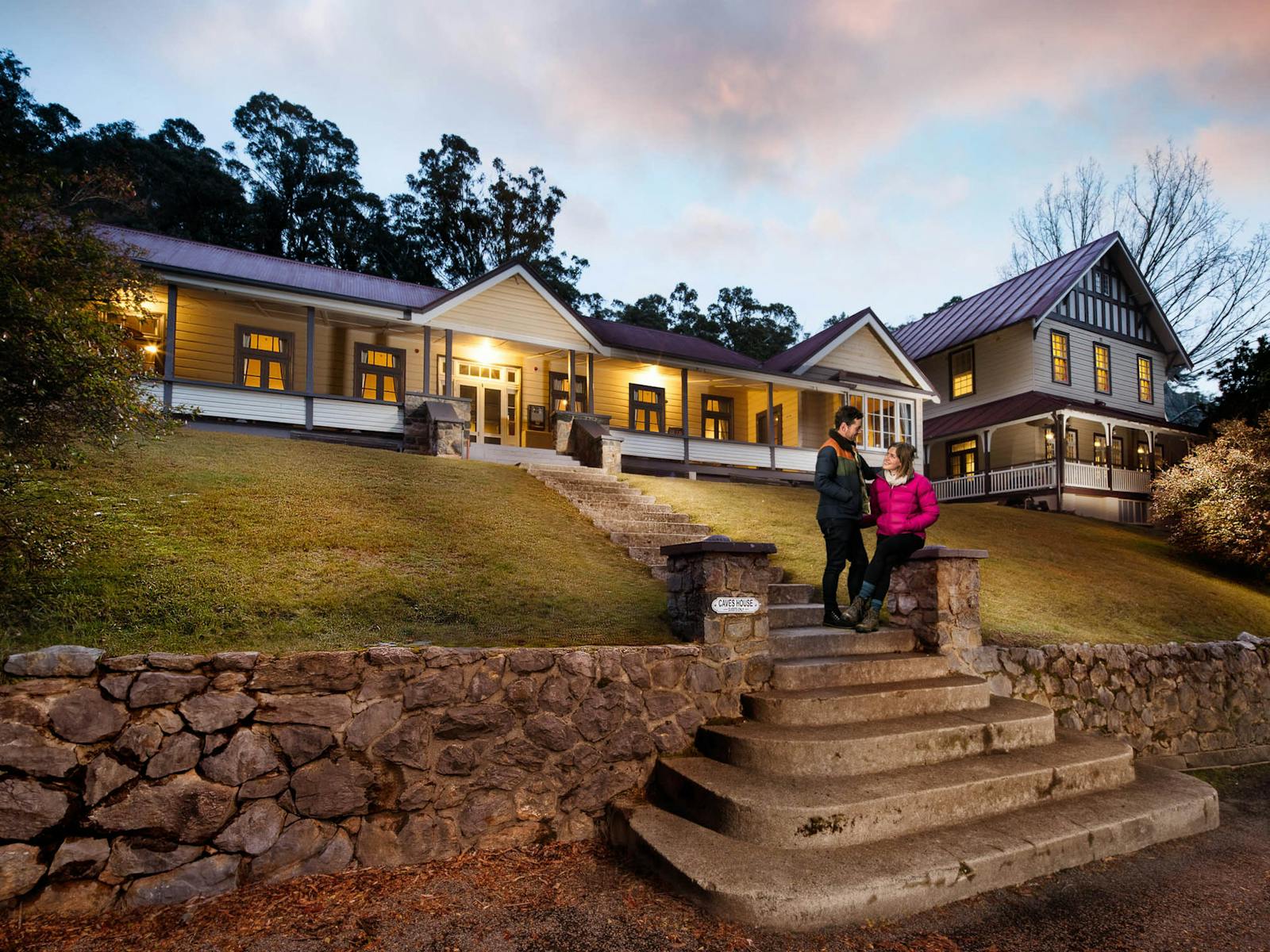 Couple standing on steps in front of caves house