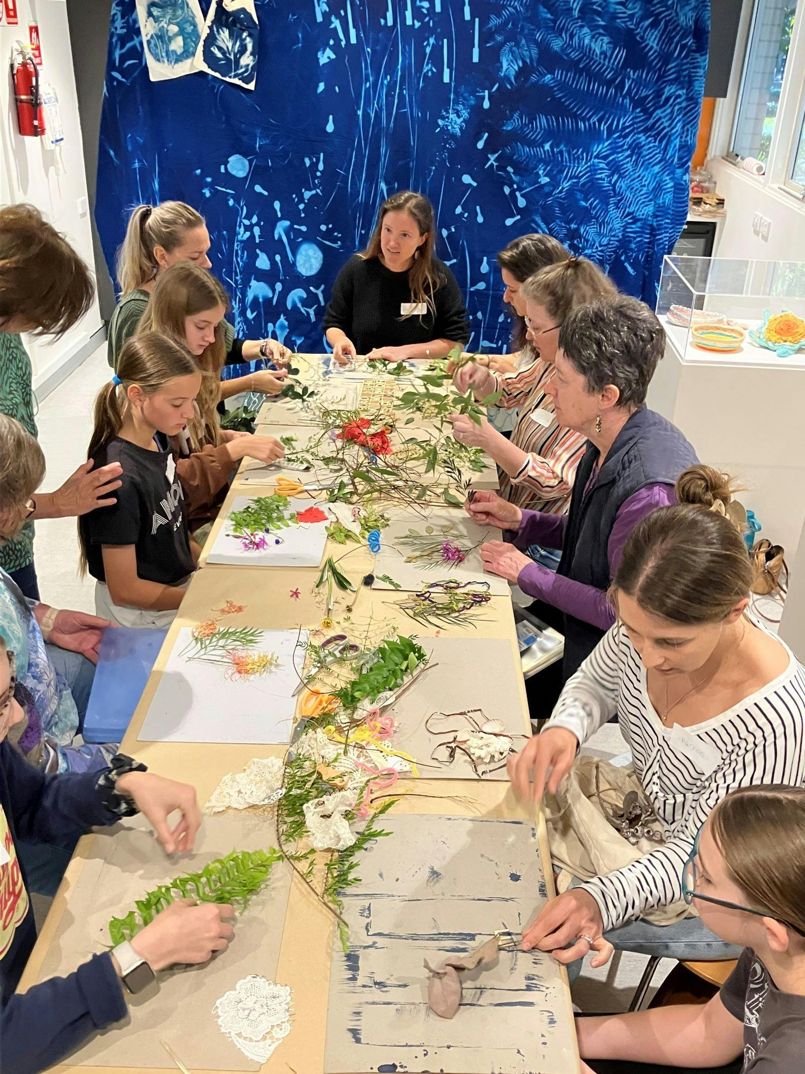 people sit at a table while they create cyanotypes