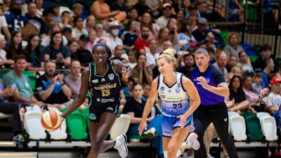 Basketball player runs down the court with defender in tow.