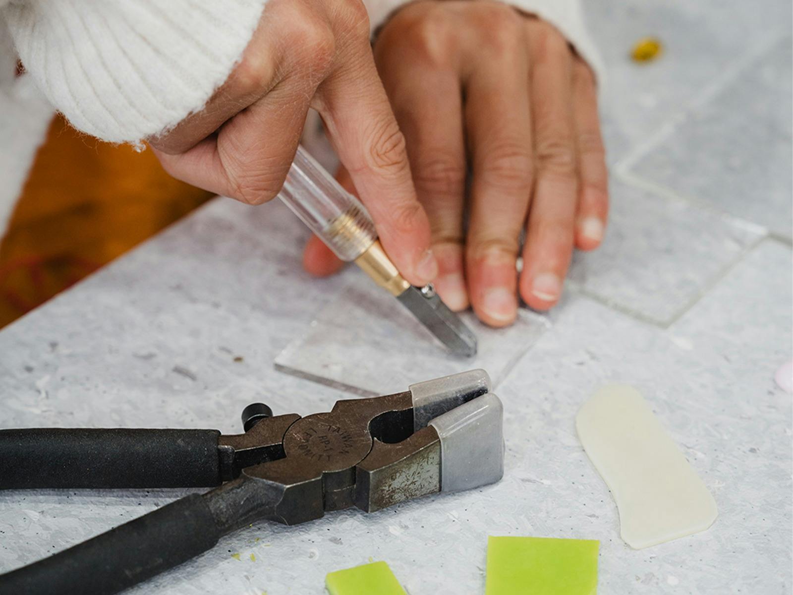 Childs hand cutting a piece of glass with special tools and matt