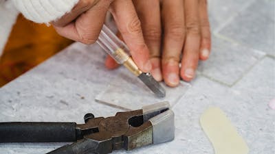 Childs hand cutting a piece of glass with special tools and matt