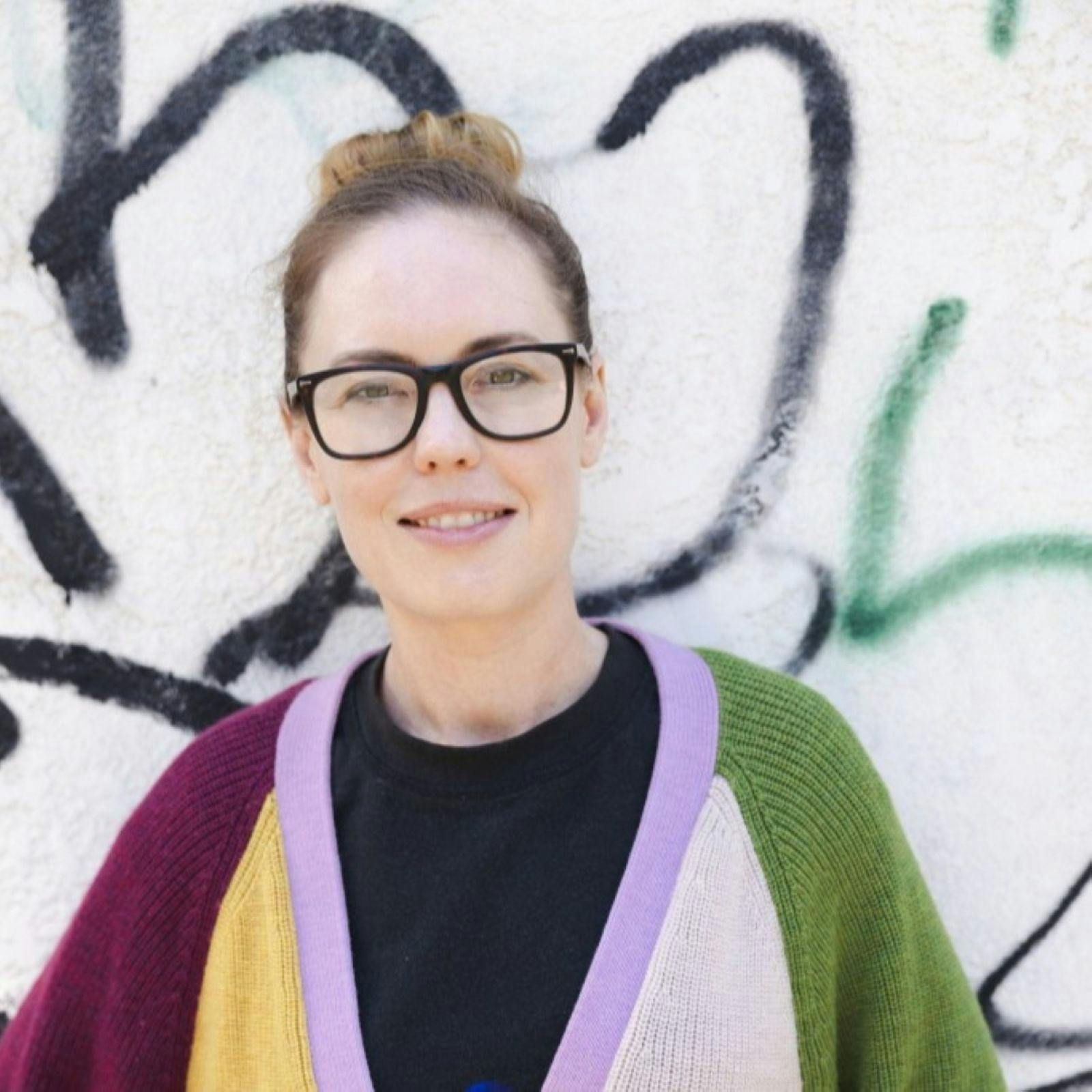 Woman stading in front of a grafitti'd wall