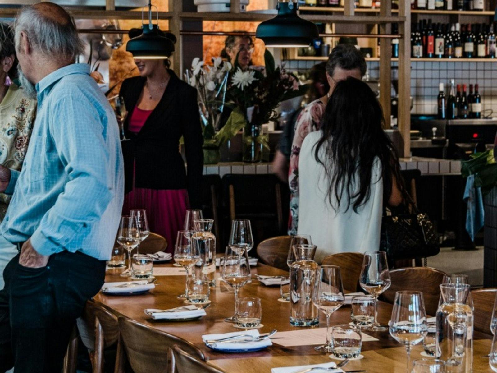 Guests inside the restaurant standing around the long table inside