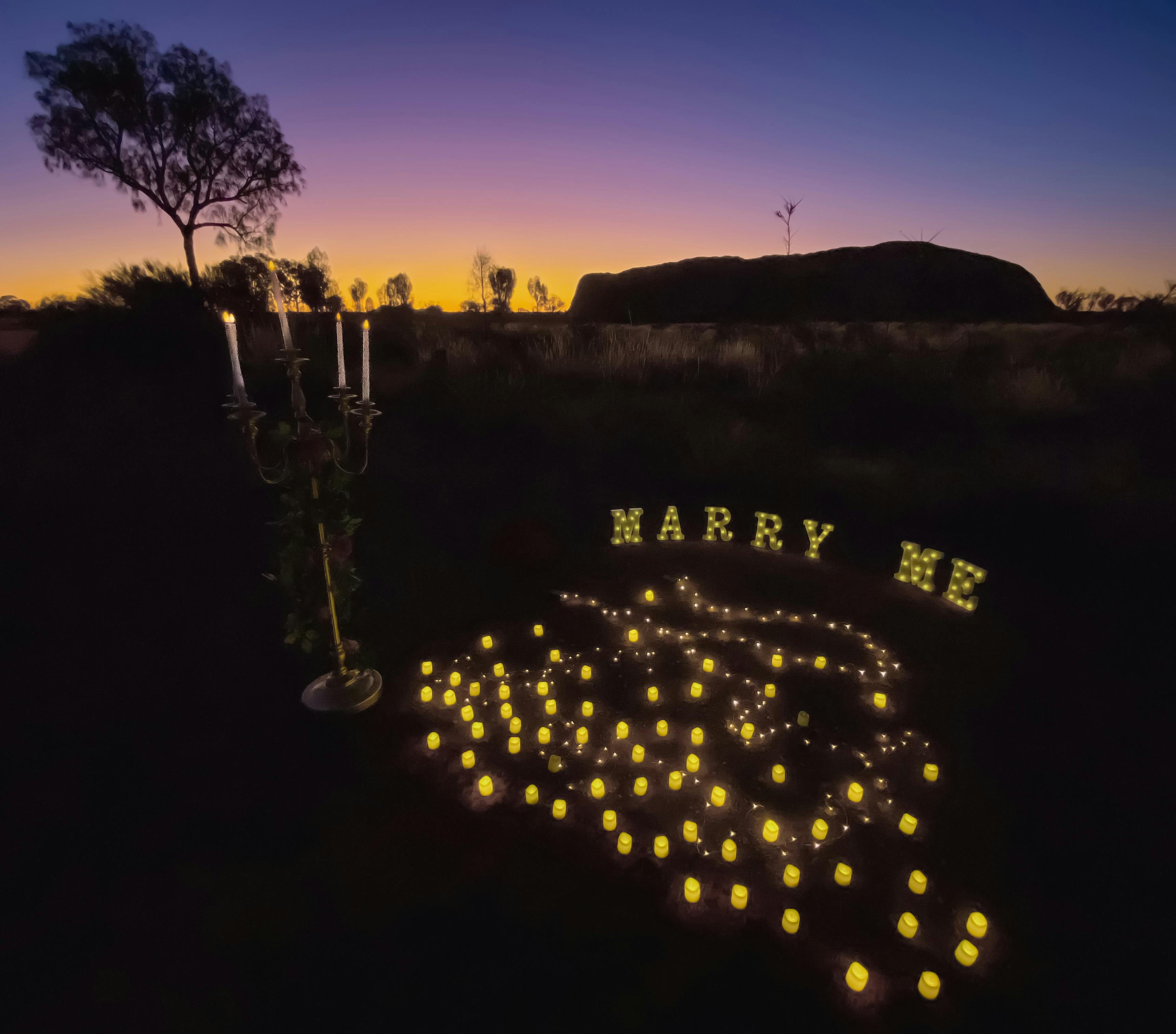 Blue, purple and yellow sunset over Uluru. Candles, and Marrry me sign.