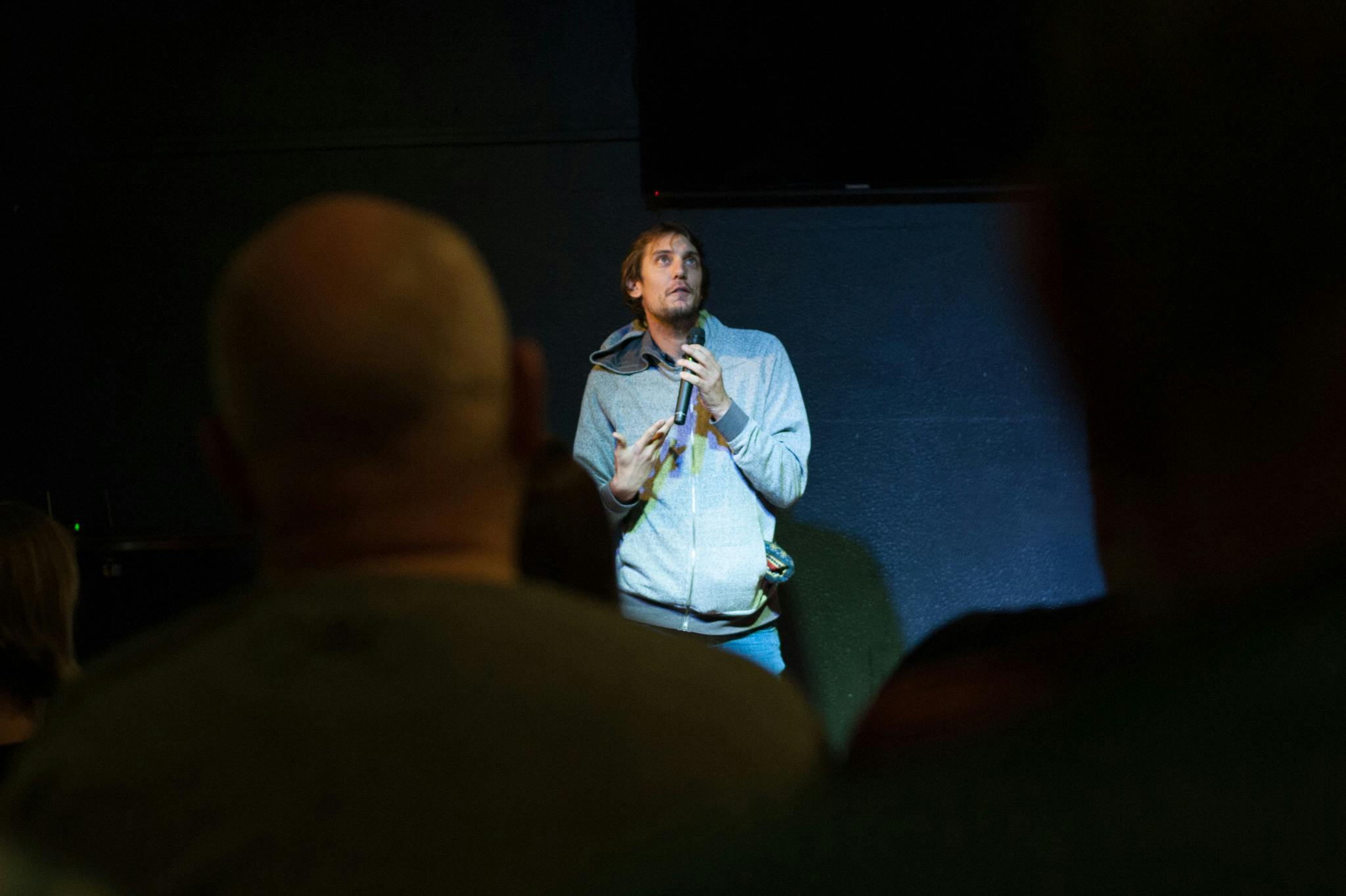 View between audience members' heads of Sydney comedian Kieran Daughton performing on stage