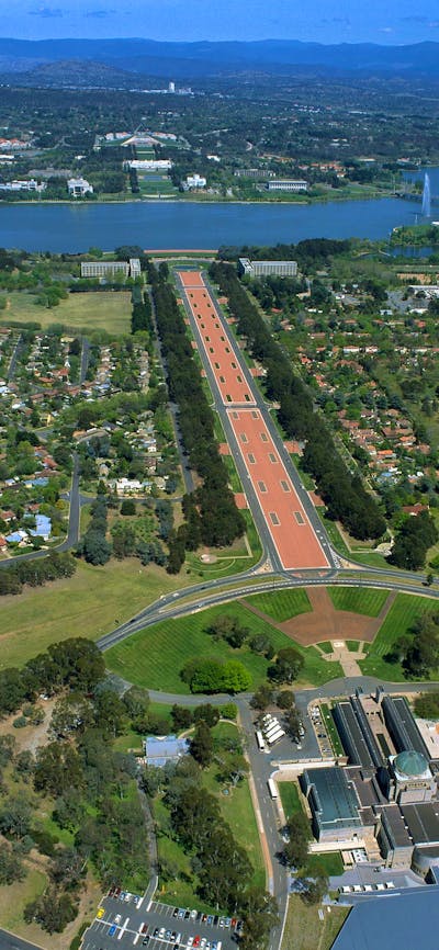 Aerial view of buildings, grassed areas, long promenade and lake.