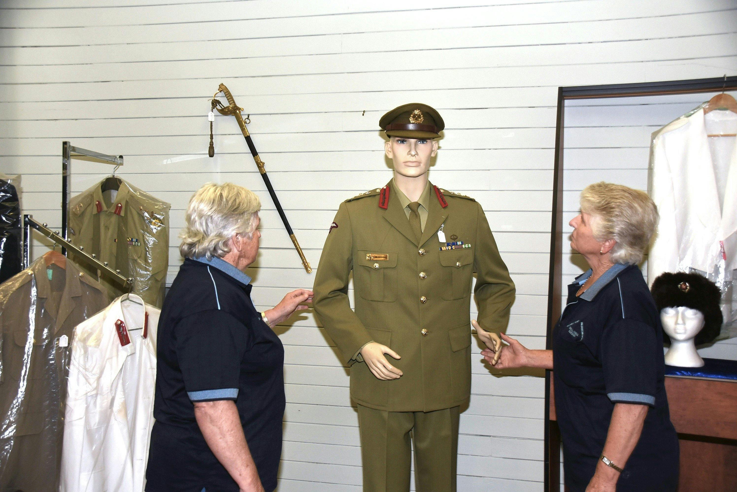 Museum volunteers with model in uniform.