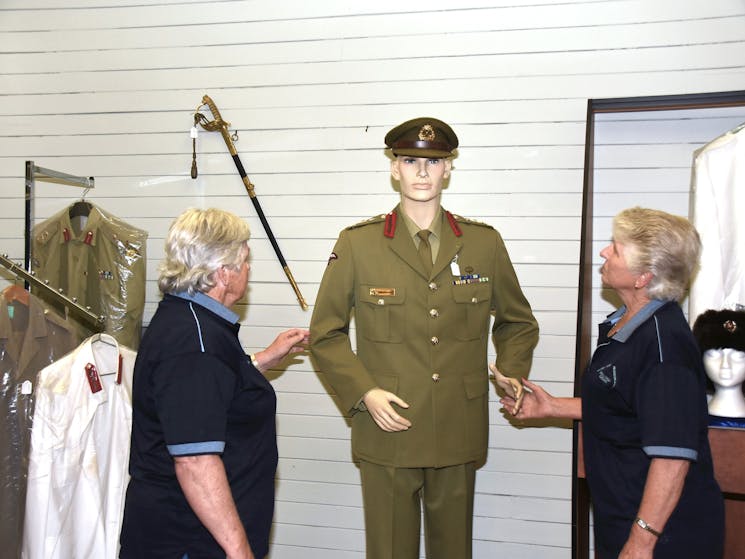 Museum volunteers with model in uniform.
