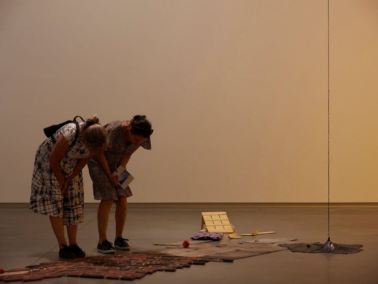 Two visitors examining a floor artwork