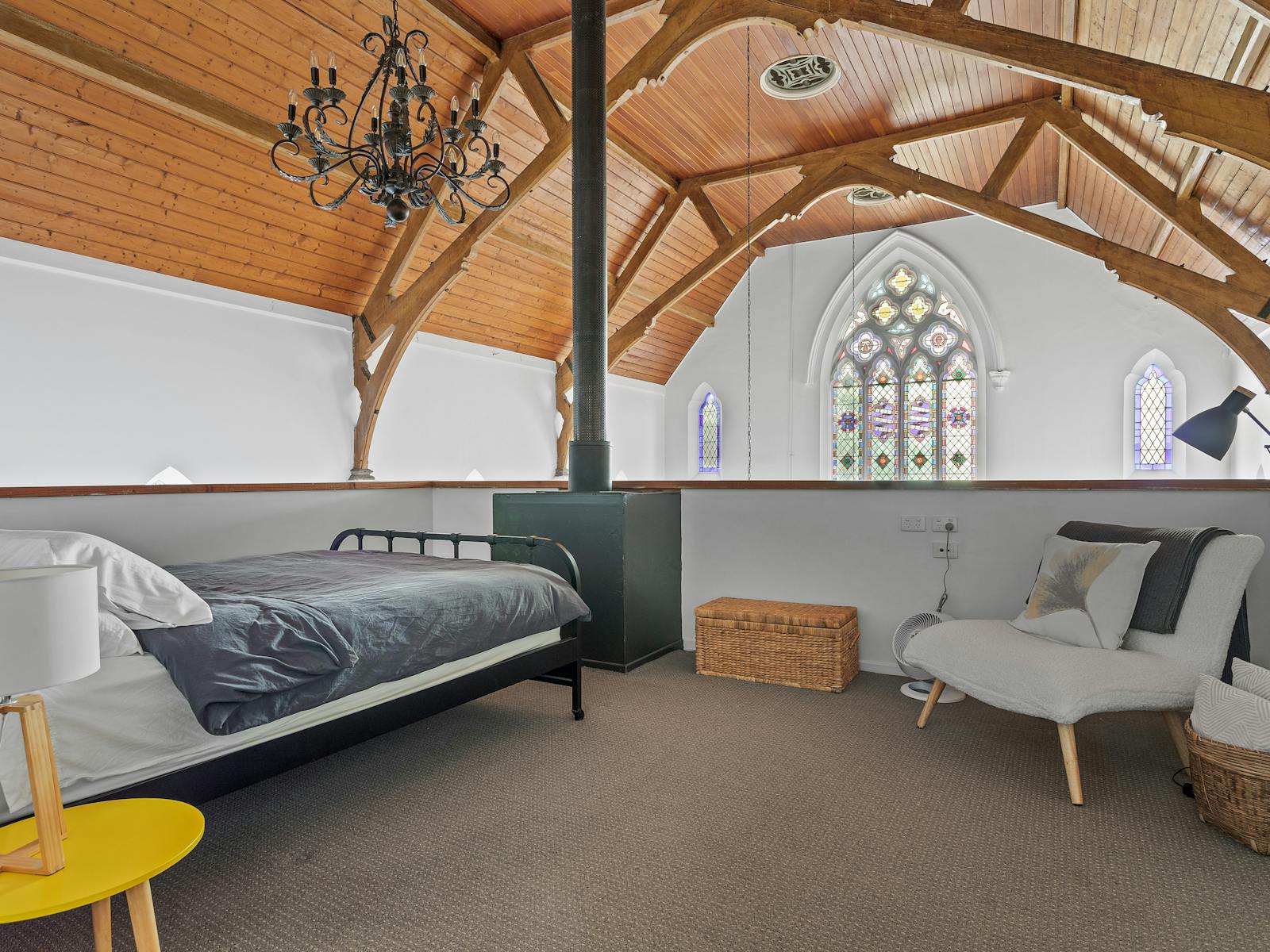 Open bedroom on a balcony, showing a view of cathedral ceilings and chandeliers over the railing