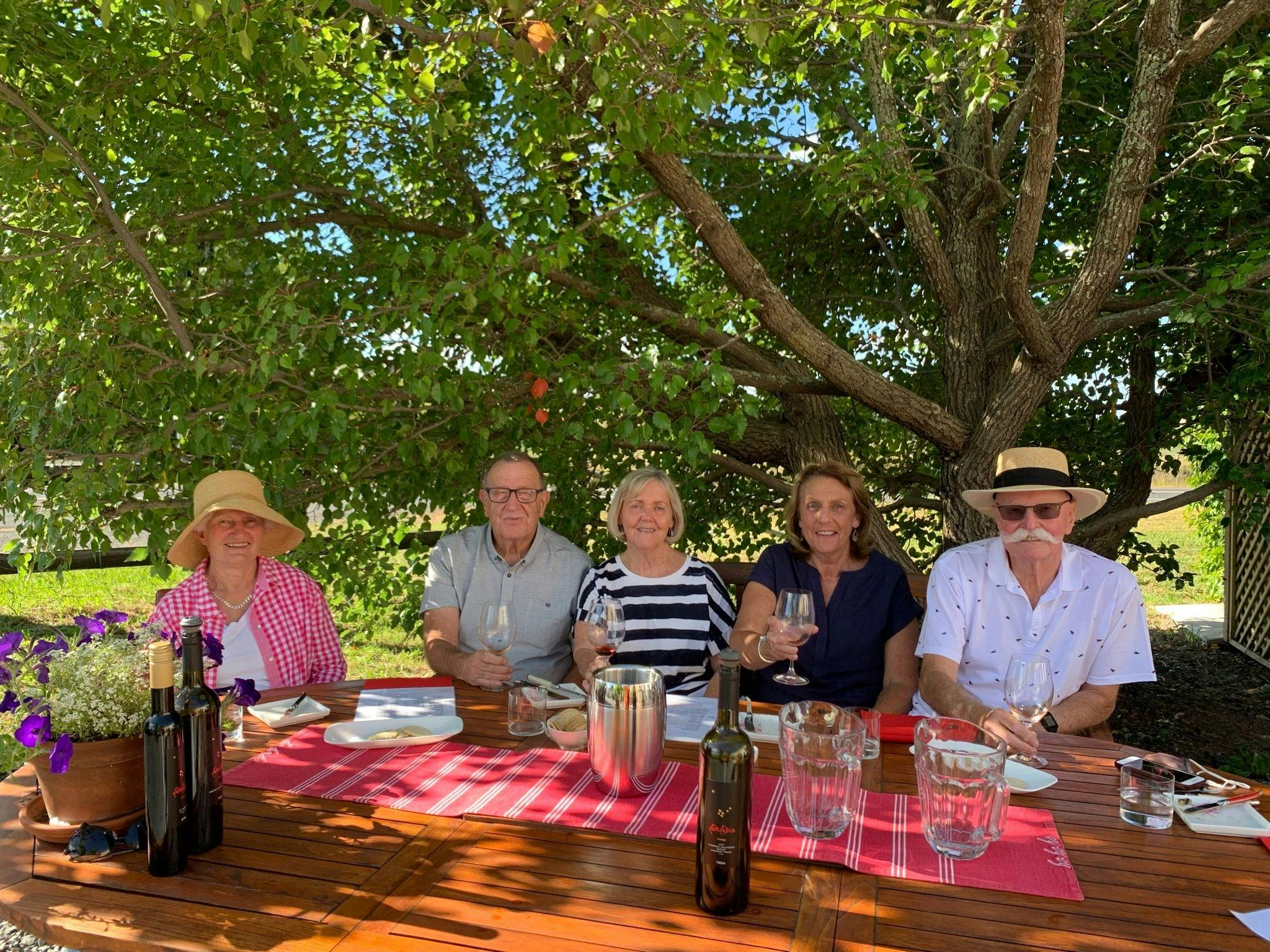 5 people sitting at table drinking wine